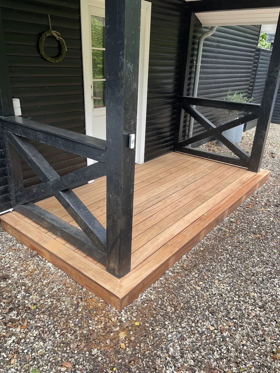 Overdækket hjørne af hardwood-terrasse med sortmalet værn - Top Hansen ApS